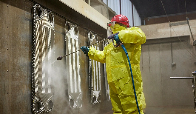 Cleaning-In- Place (CIP) durch einen Industriereiniger in einem gelben Schutzanzug.