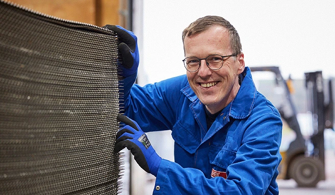 Ein BUCHEN Mitarbeiter steht rechts neben einem Stapel an Platten, während er mit der Hand drüber streicht.